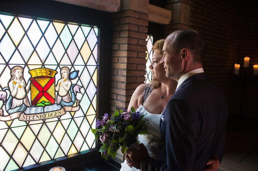 Bruidspaar bij een glas-in-loodraam met het wapen van Steenbergen