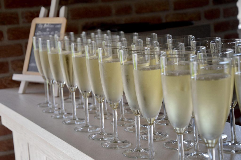 Een rij glazen prosecco op een witte bar
