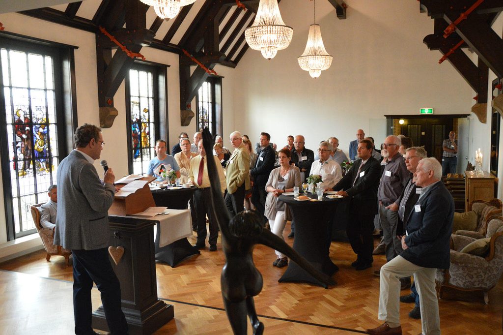 Een presentatie in de trouwzaal, met gasten aan statafels onder kroonluchters